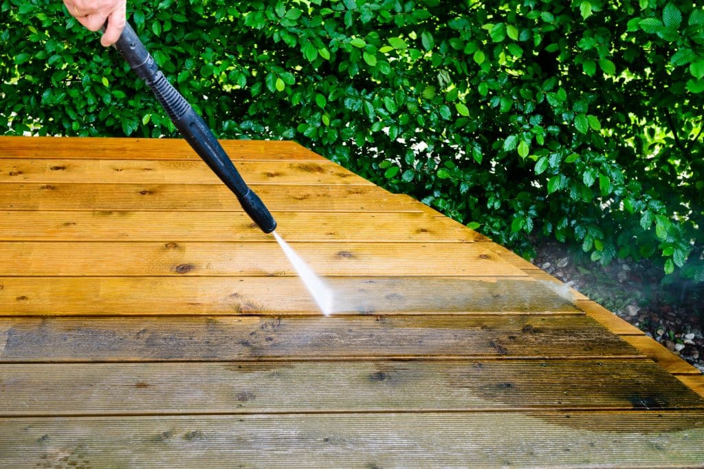 cleaning terrace with a power washer - high water pressure cleaner on wooden terrace surface